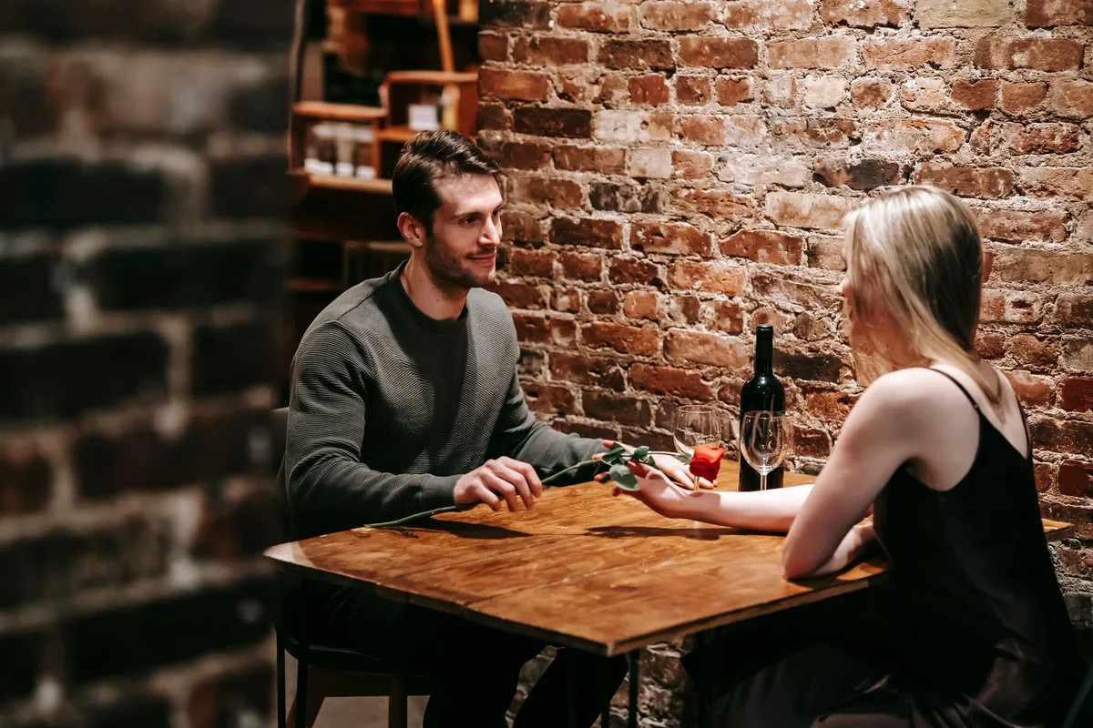 Un couple dînant au restaurant, portant des bagues visibles à l'annulaire gauche.
