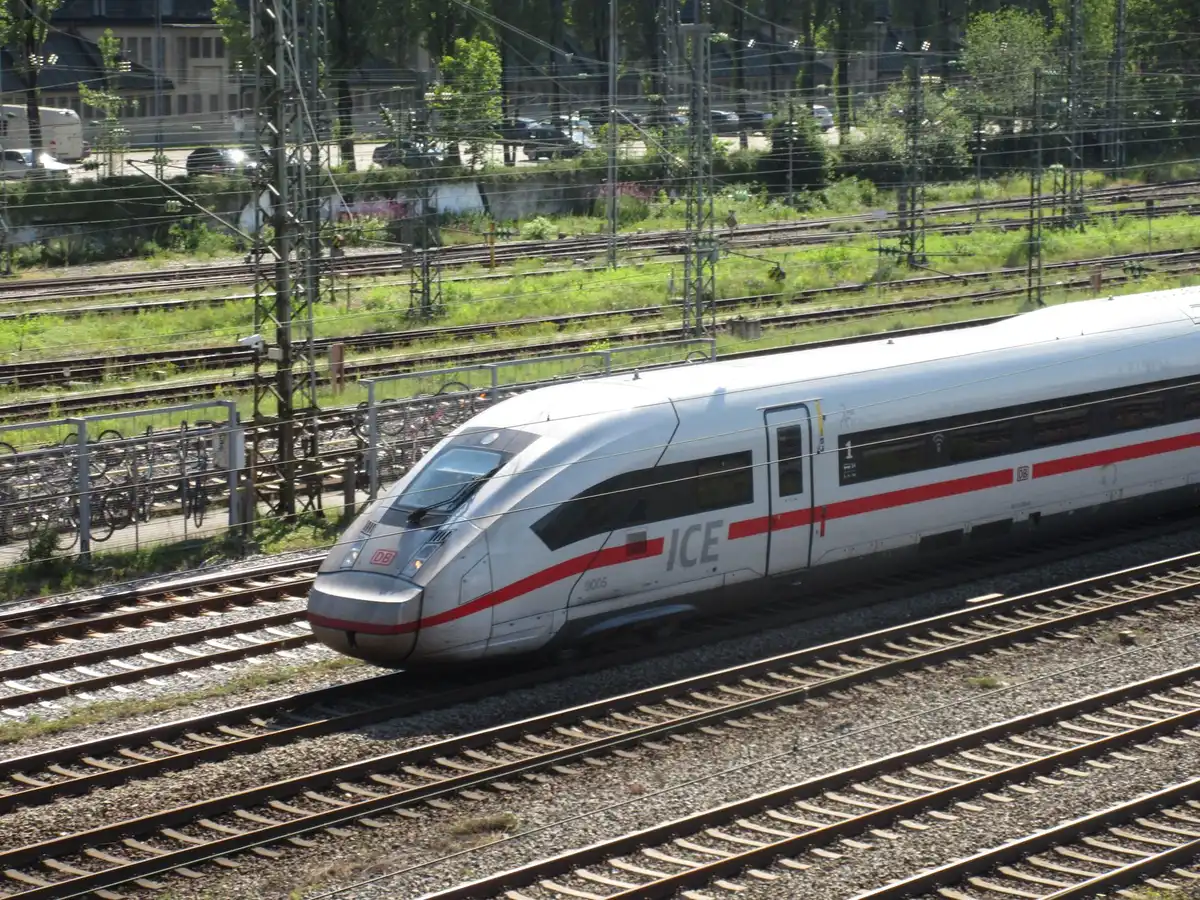 Voyageurs attendant dans une gare, tableaux d'affichage indiquant des retards et annulations de trains