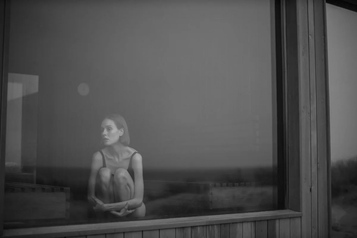 Femme seule regardant par la fenêtre, moment de solitude et de mélancolie après une séparation