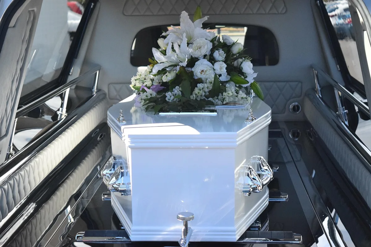 Personnes anonymes près d'une stèle en bord de lac, bouquets déposés