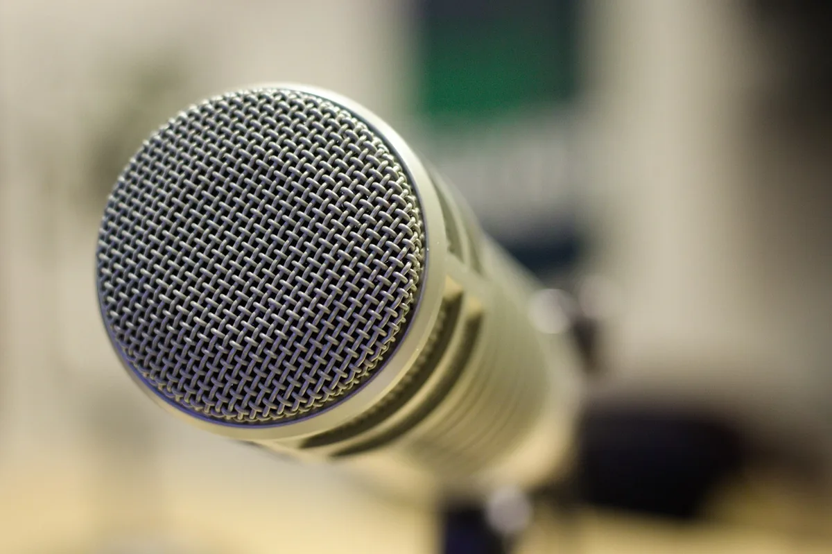 Microphone de studio radio, tasse et carnet sur une table, ambiance intime et discrète