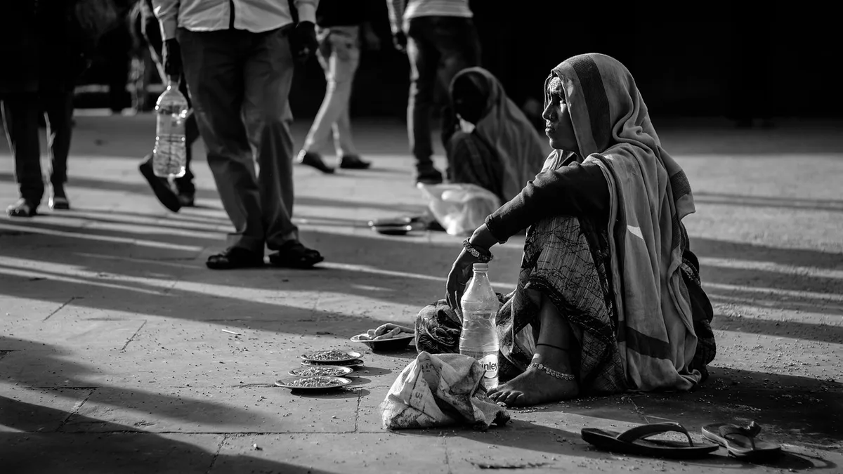 Main anonyme déposant une pièce dans une tirelire solidaire avec fiches de projets floues