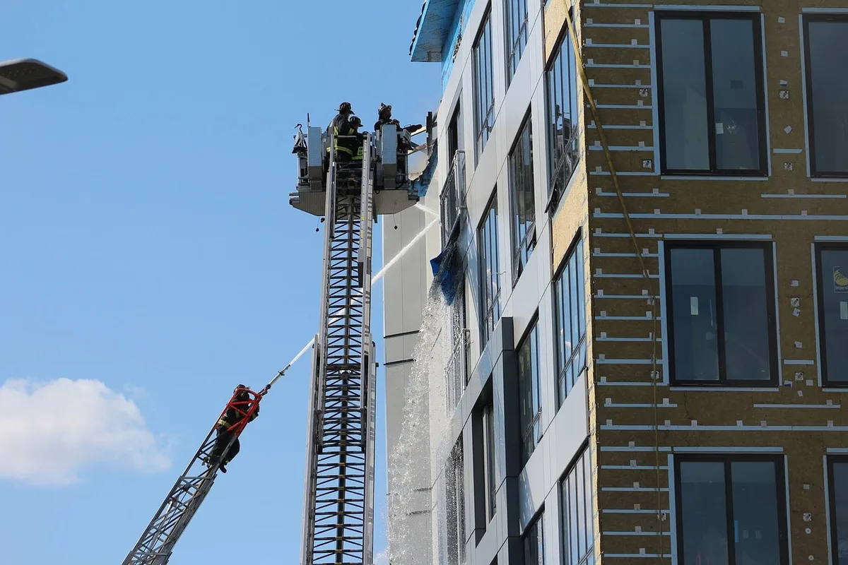 Bâtiment du centre-ville en feu, fumée visible et barrières de sécurité