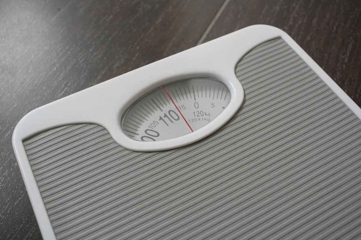 Adolescente devant une balance se regardant dans un miroir, symbole du début d'un trouble alimentaire
