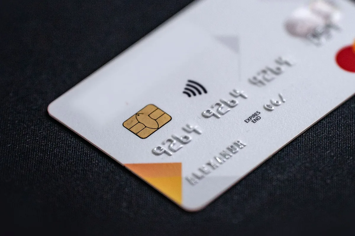 Mains anonymes montrant une carte bancaire et notifications de fraude sur un écran