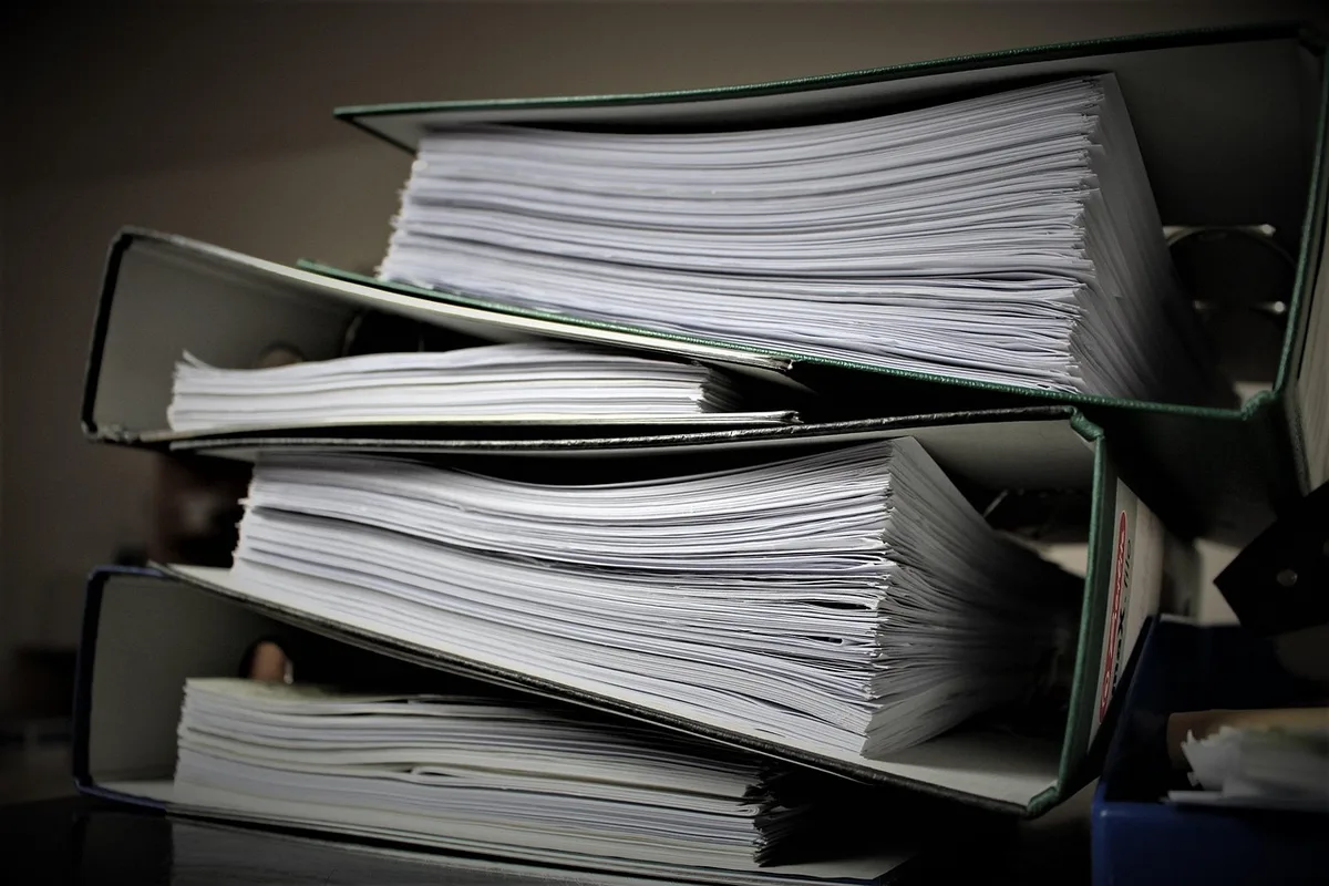 Pile de dossiers administratifs de surendettement sur une table